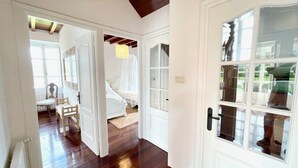 A hallway leading to a bedroom with a bed, a chair, and a window. - The Cliffs - A Casa de Mercedes (Mañon)