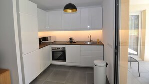 A compact kitchen with white cabinets, a microwave, a stove, and a sink.