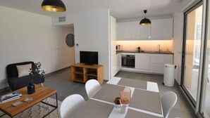 A compact living space with a dining area, a kitchenette, a TV, and a sofa.