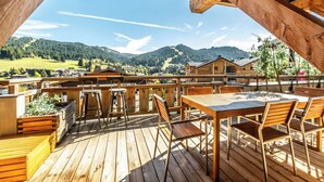 Eine Holzterrasse mit Tisch und Stühlen, mit Blick auf eine Berglandschaft.