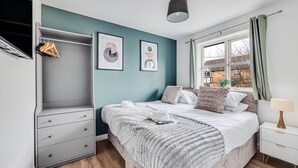 A bedroom with a bed, a wardrobe, a bedside table, and a window with curtains.