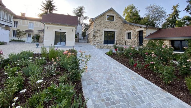 A courtyard with a stone pathway leading to a stone house with a dark door and a window. - Charming Renovated Cottage in 2-Hectare Park with Fishing Pond, Near Forest, Close to Versailles (Senlisse)