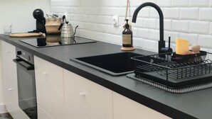 A modern kitchen with a black countertop, white cabinets, a black sink, and a coffee machine. - Charming Renovated Cottage in 2-Hectare Park with Fishing Pond, Near Forest, Close to Versailles (Senlisse)