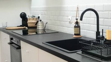 Una cocina moderna con encimera negra, armarios blancos y un lavamanos negro, además de una cafetera.