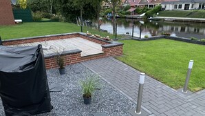 Un patio con jardinera de ladrillo, grava y plantas en macetas.