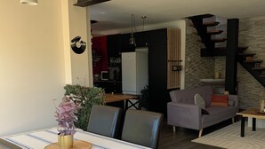 A dining area with a table set for two, a sofa, and a kitchen in the background. - Cosy house in peaceful setting 10 minutes from Avignon (Le Pontet)
