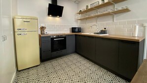 A compact kitchen with a vintage refrigerator, modern appliances, and a patterned floor. - Magnificent T2 hyper center, hyper equipped (La Rochelle)