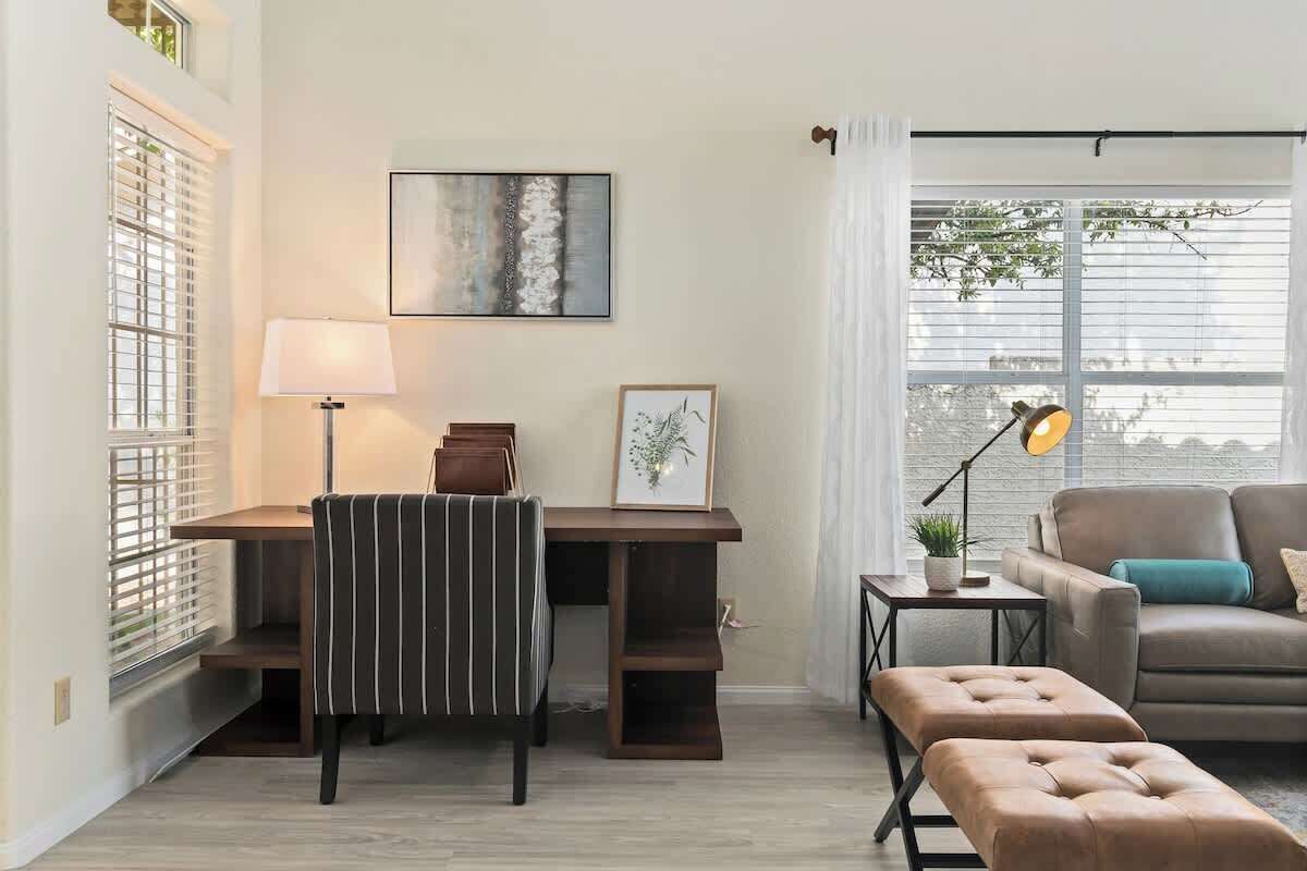 Een moderne woonkamer met een bureau, gestreepte stoel, bank en voetenbankje.