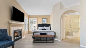 A bedroom with a bed, a TV mounted above a fireplace, and a bench. - ❤️New 4BR/3Ba with Pool, 9 miles to LV Strip! (Henderson)