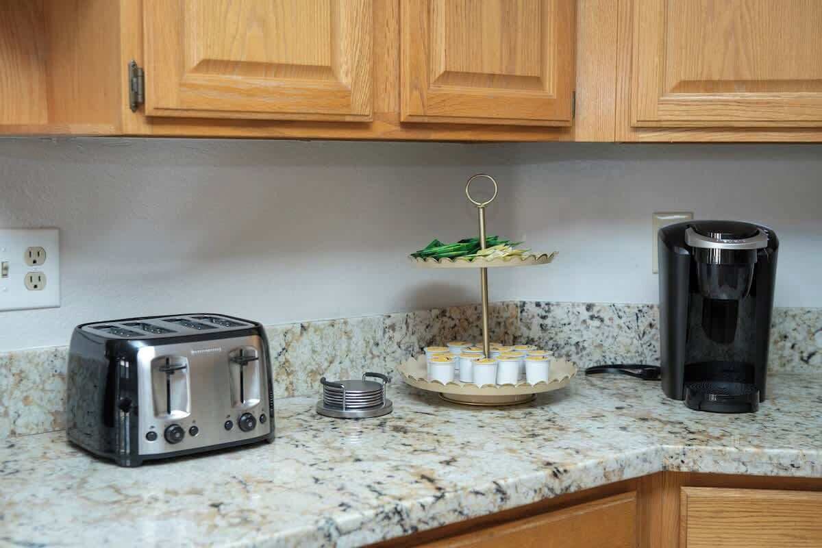 A kitchen with wooden cabinets, a toaster, a coffee maker, and a three-tiered tray with food items.