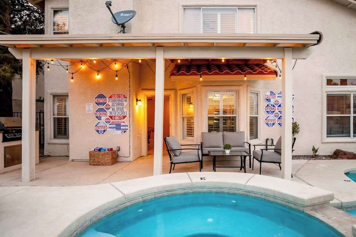 A pool area with a covered patio, outdoor seating, and multiple caution signs.