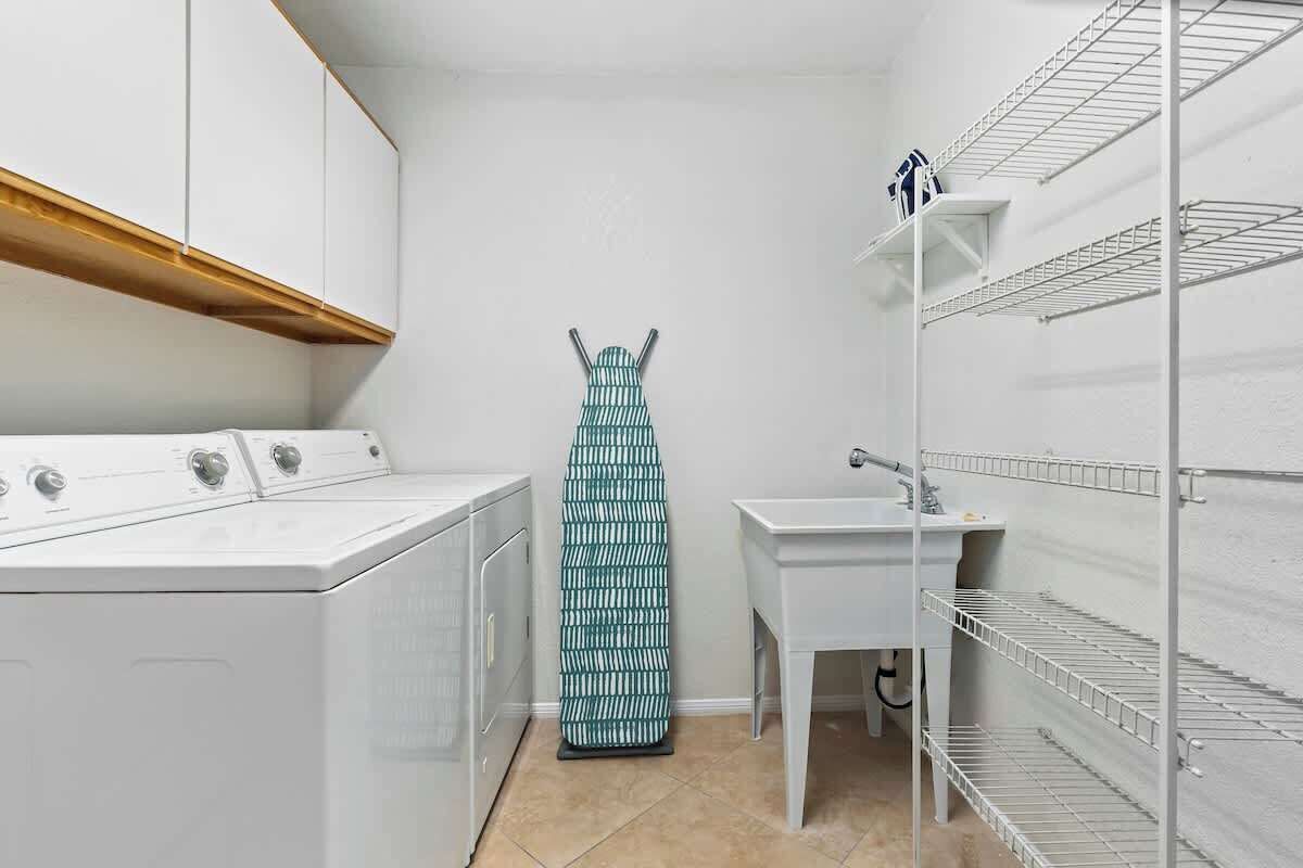 A laundry room with a washing machine, dryer, and ironing board.