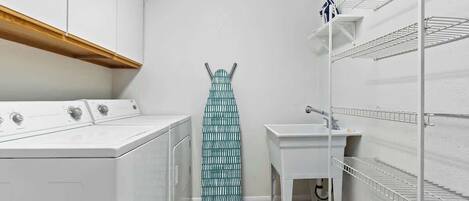 A laundry room with a washing machine, dryer, and ironing board.