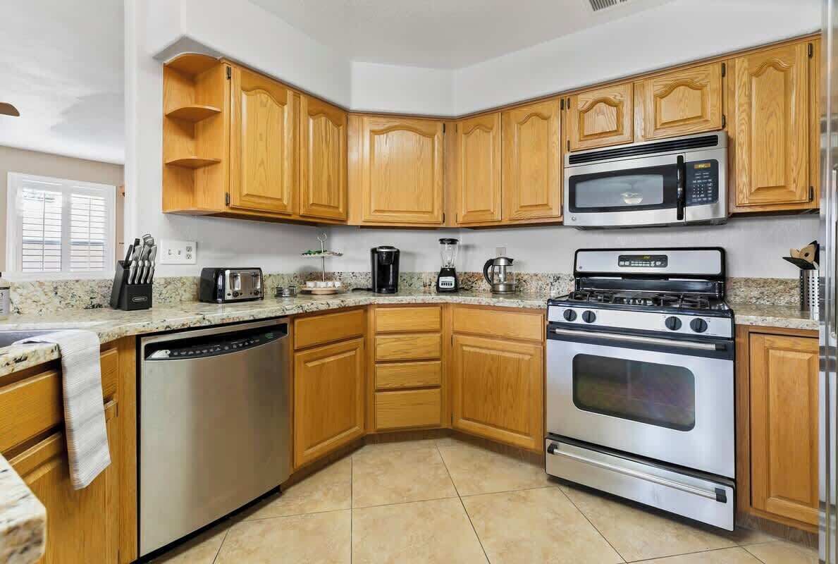 A kitchen with wooden cabinets, stainless steel appliances, and a granite countertop.