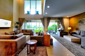 A modern living room with a sofa, a coffee table, and a TV mounted on the wall.