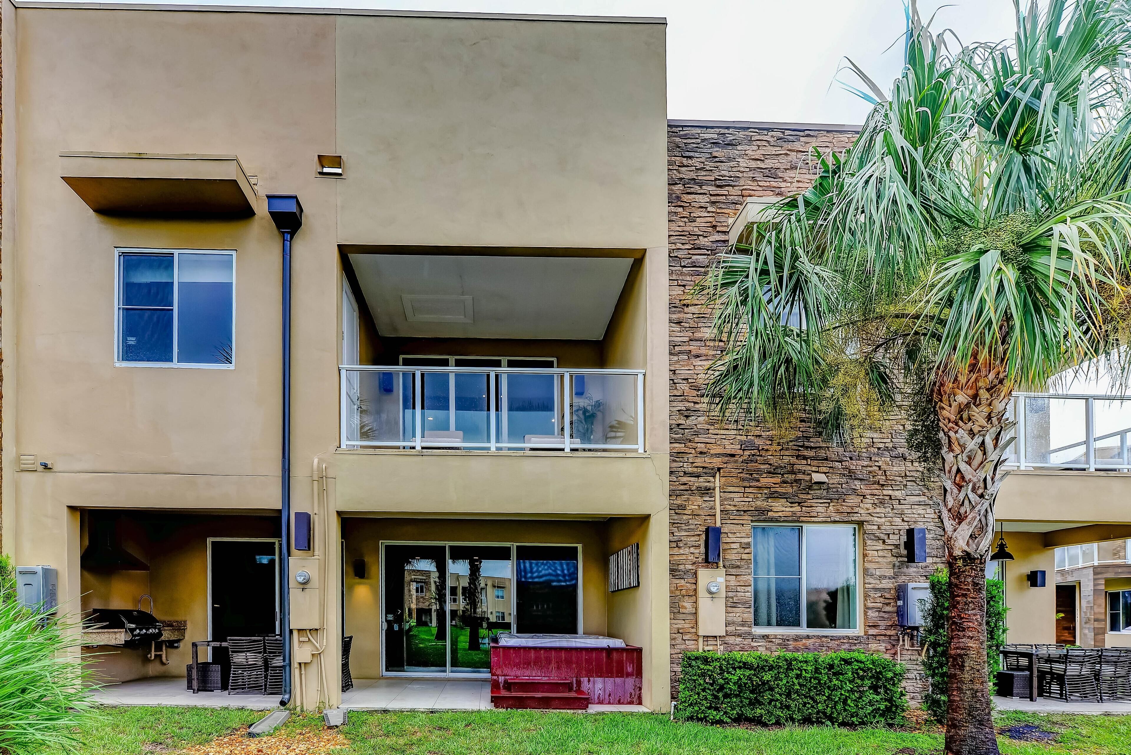 A two-story building with a flat roof, a balcony on the upper floor, and a small front porch area.