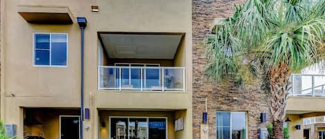 A two-story building with a flat roof, a balcony on the upper floor, and a small front porch area.