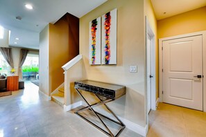 A modern interior with a staircase, a console table, and a door. - Magical Village Gem (Kissimmee)