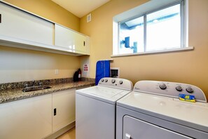 A laundry area with a washing machine and dryer, a sink, and a window with a view.