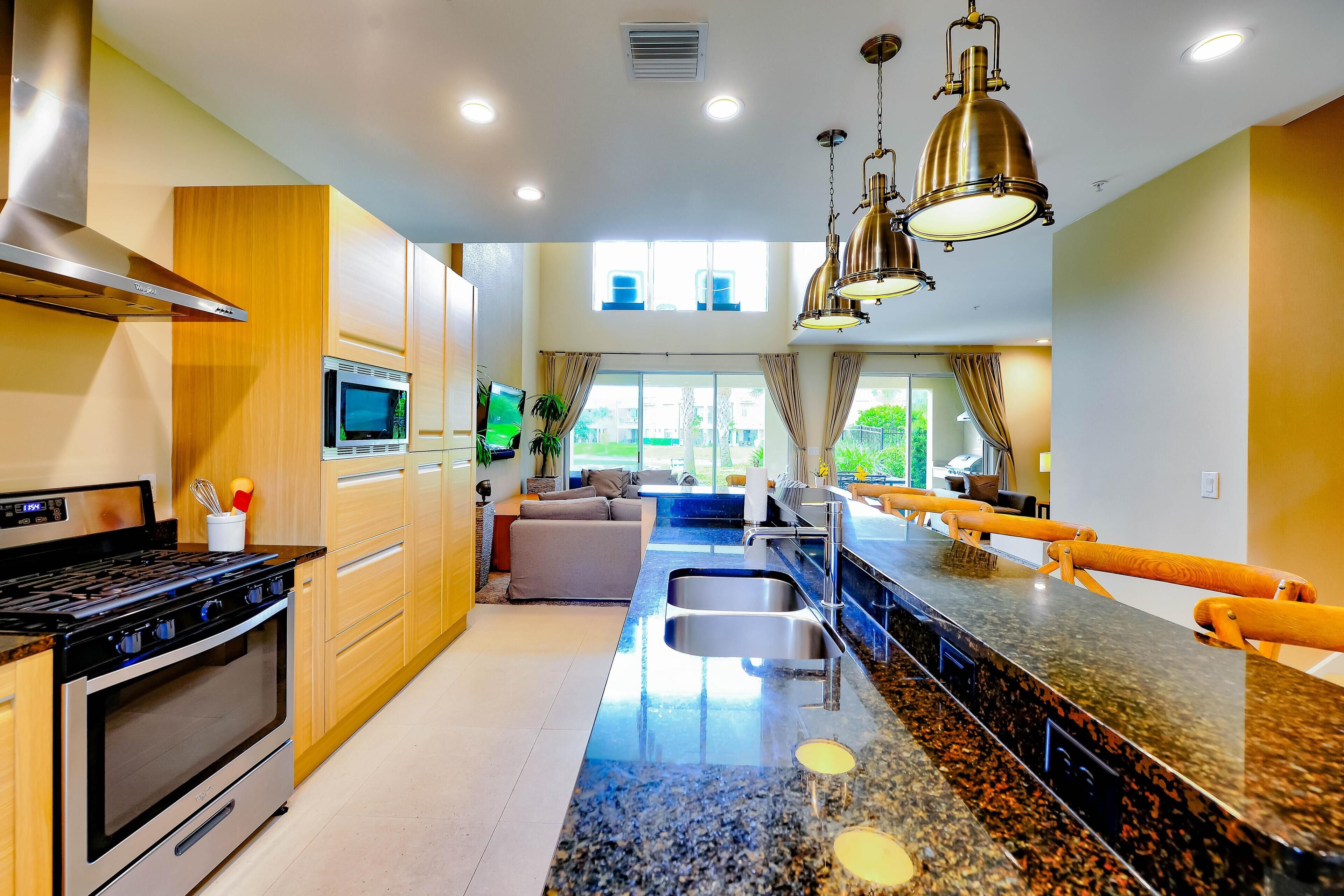 A modern kitchen with a stainless steel stove, a microwave, and a large island with a sink.