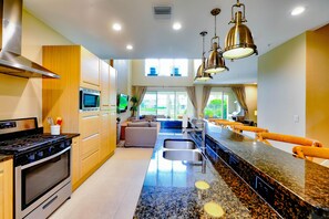A modern kitchen with a stainless steel stove, a microwave, and a large island with a sink.