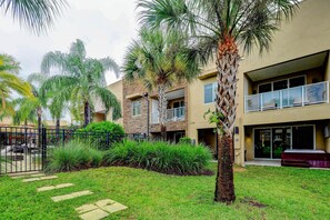 A modern building with a two-story structure, a covered outdoor area, and a well-maintained garden with palm trees and shrubs.