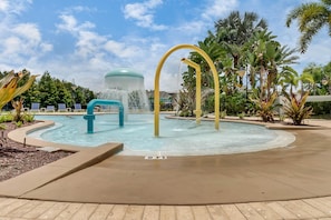 Ein Poolbereich mit Wasserspiel, Liegestühlen und tropischer Bepflanzung.