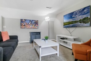 Uma sala de estar moderna com televisão de tela plana, um quadro, lareira e mesa de centro.
