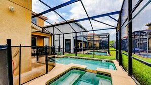 A swimming pool area with a glass enclosure, a covered seating area, and a view of adjacent buildings. - Paradise Palms Resort, Just Minutes From Disney!!!! (Kissimmee)