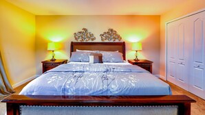 A neatly made bed with a floral bedspread, two bedside lamps, and a decorative wall piece above the headboard. - Paradise Palms Resort, Just Minutes From Disney!!!! (Kissimmee)