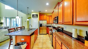 A kitchen with wooden cabinets, a stainless steel refrigerator, and a granite countertop. - Paradise Palms Resort, Just Minutes From Disney!!!! (Kissimmee)