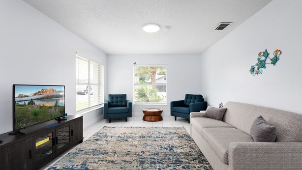 A living room with a TV, two armchairs, a sofa, a coffee table, and a patterned rug. - Pearl Villa (Kissimmee)