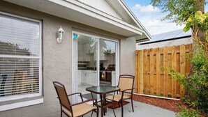 A patio with a table and chairs, a wooden fence, and a house with a window and a door. - Pearl Villa (Kissimmee)