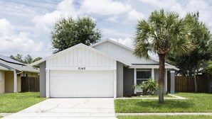 A single-story house with a white garage, numbered 5365, and a small front yard with a palm tree. - Pearl Villa (Kissimmee)