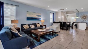A modern living room with a sofa, coffee table, and dining area. - Luxurious Vacation Home With Private Pool!!! (Kissimmee)