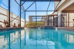 A swimming pool with a glass enclosure, surrounded by a white wall and a metal fence. - Luxurious Vacation Home With Private Pool!!! (Kissimmee)
