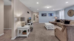 A living room with a sectional sofa, a white coffee table, a TV, and a lamp. - Luxurious Vacation Home With Private Pool!!! (Kissimmee)