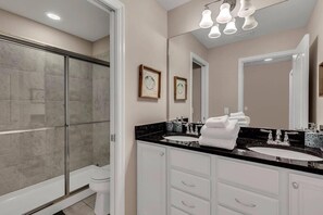 A modern bathroom with a glass-enclosed shower, two sinks, and a large mirror.