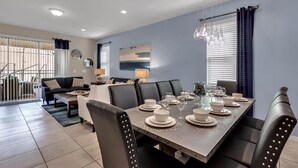 A dining area with a long table set for six, surrounded by black leather chairs. - Luxurious Vacation Home With Private Pool!!! (Kissimmee)
