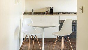 Eine moderne Küche mit weißen Schränken, einer zentralen Kochinsel mit zwei weißen Stühlen und Holzdielen.