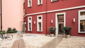 Ein rotes Gebäude mit weiß gefassten Fenstern und Türen, einem Kieshof und zwei Kübelpflanzen.