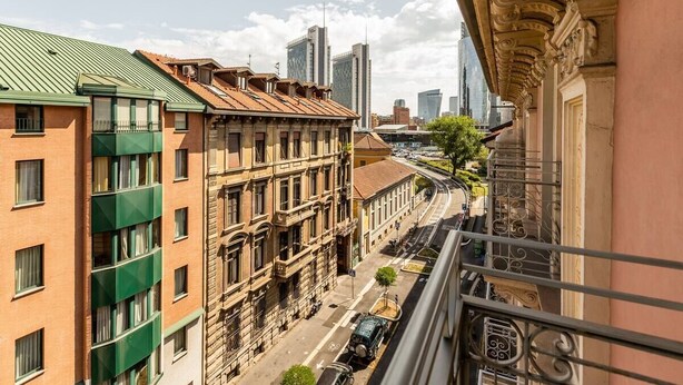 Straßenansicht mit historischen Gebäuden, einem Zug und modernen Wolkenkratzern im Hintergrund.