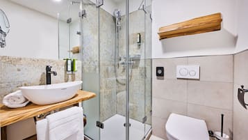 Un baño moderno con ducha de vidrio, lavamanos blanco y retrete.