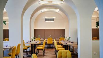 Uma sala de jantar moderna com cadeiras e mesas amarelas, tetos em arco e iluminação pendente.