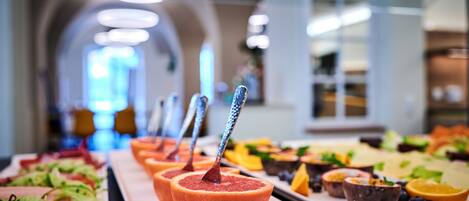 A buffet with various food items and a spoon in a bowl.
