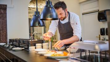 Un chef preparando comida en un mostrador de buffet con diversos platos y utensilios.