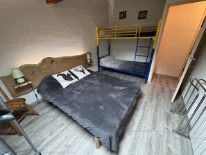 Un dormitorio con literas, un cabecero de madera, una mesita de noche con lámpara y una silla.