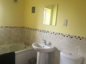 Et badeværelse med badekar, håndvask og toilet.