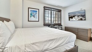 Ein Schlafzimmer mit einem Bett, einem Schreibtisch und zwei gerahmten Bildern an der Wand.