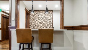 A bar area with two stools and a wall decorated with circular logs. - Ski-In Ski-Out Condo at Deer Valley (Park City)